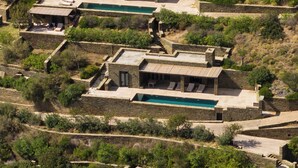 A stone villa with multiple pools and outdoor seating areas, surrounded by lush vegetation. - Onar Andros (Andros)
