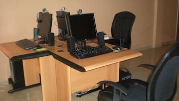 Un escritorio de madera con dos monitores de computadora, un teclado y un ratón. Hay dos sillas de oficina negras.