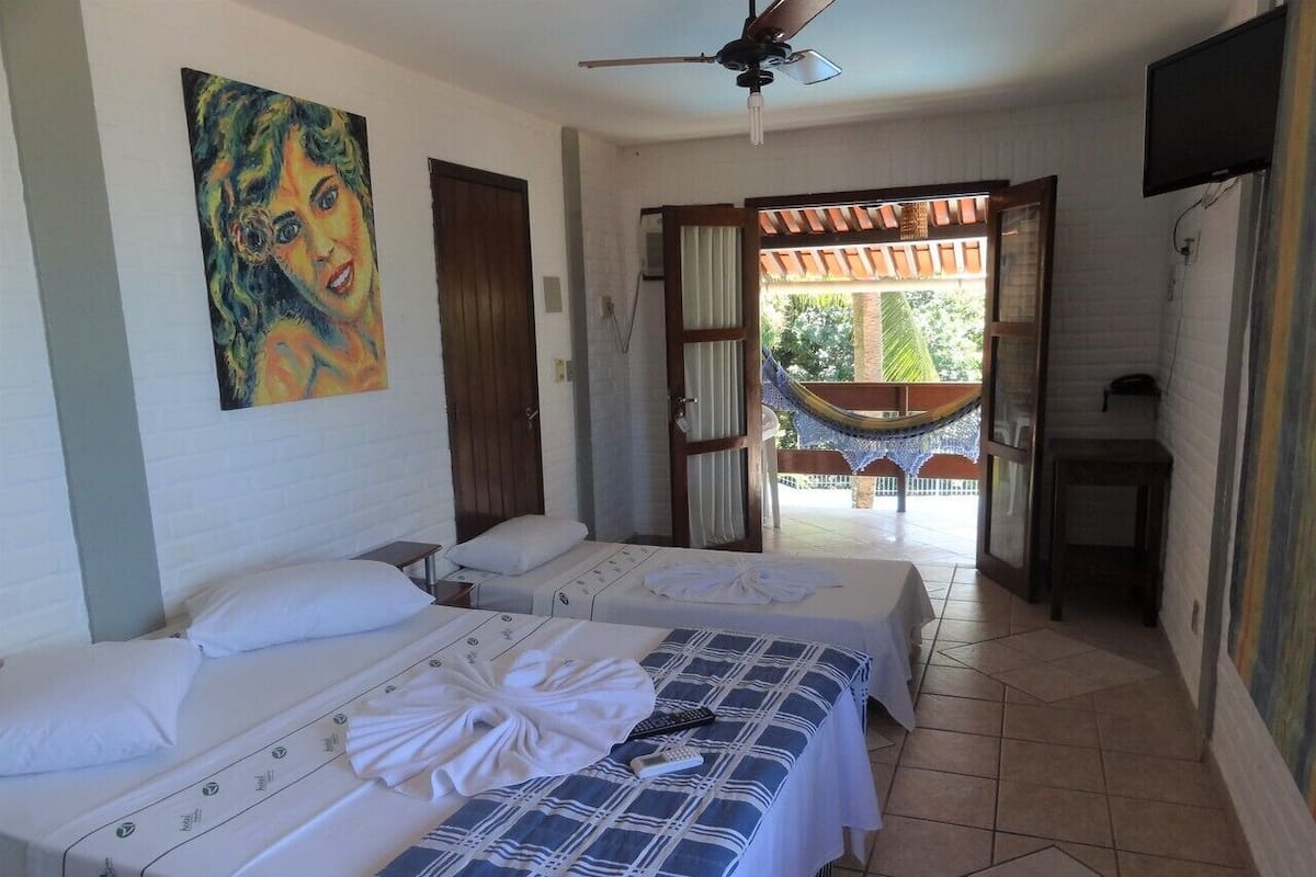 A hotel room with two beds, a ceiling fan, a TV, and a view of the outside.