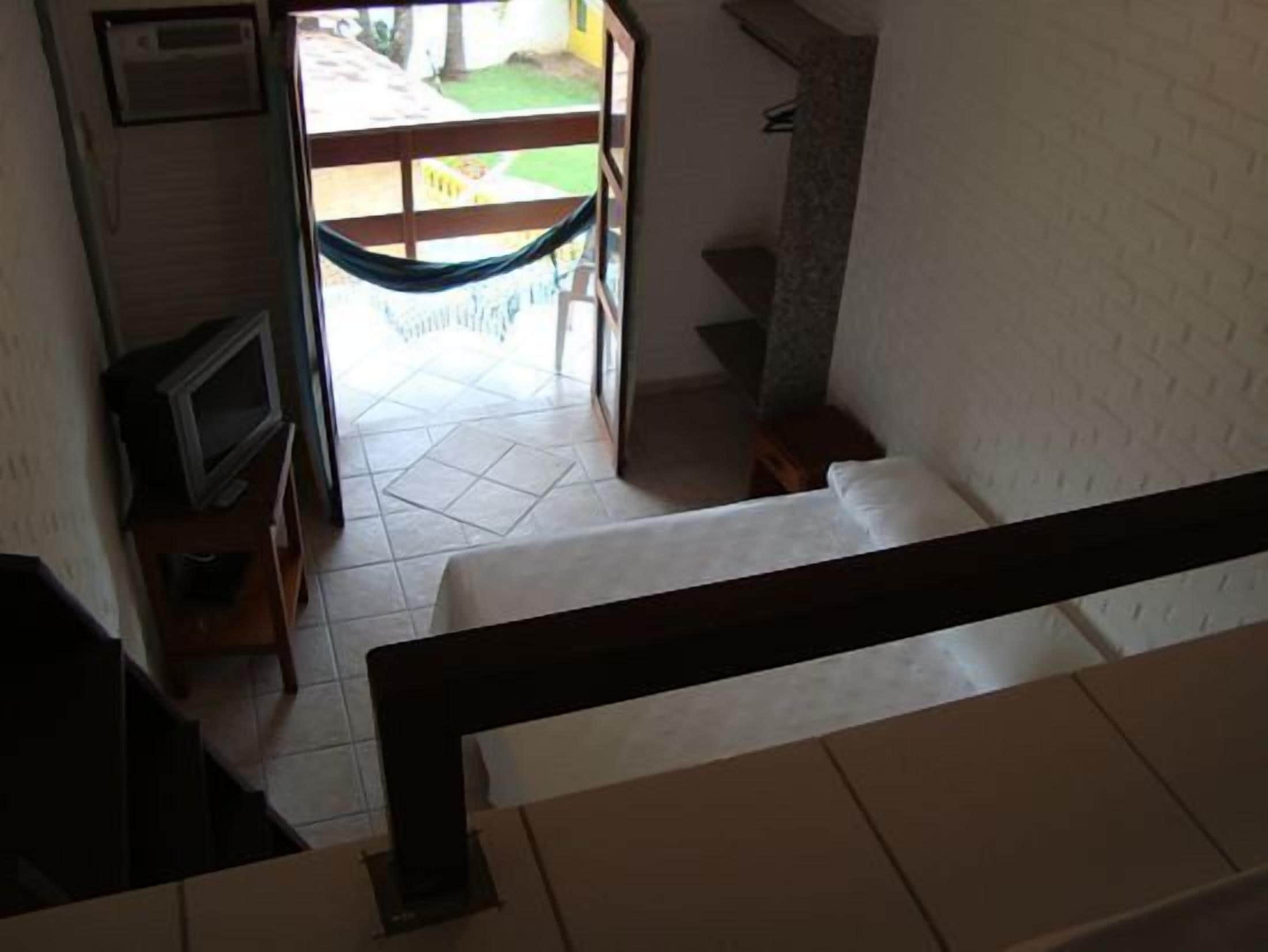 Een trap die leidt naar een kamer met een hangmat, een televisie en een betegelde vloer.