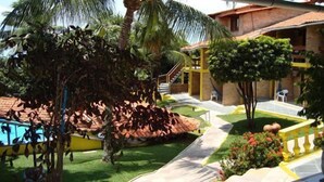 Zona de piscina con tobogán, palmeras y un edificio con tejado de azulejos.