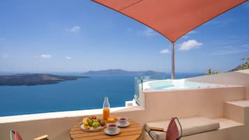 Una terraza con una mesa lista para el desayuno, con vistas al mar y a un paisaje montañoso.