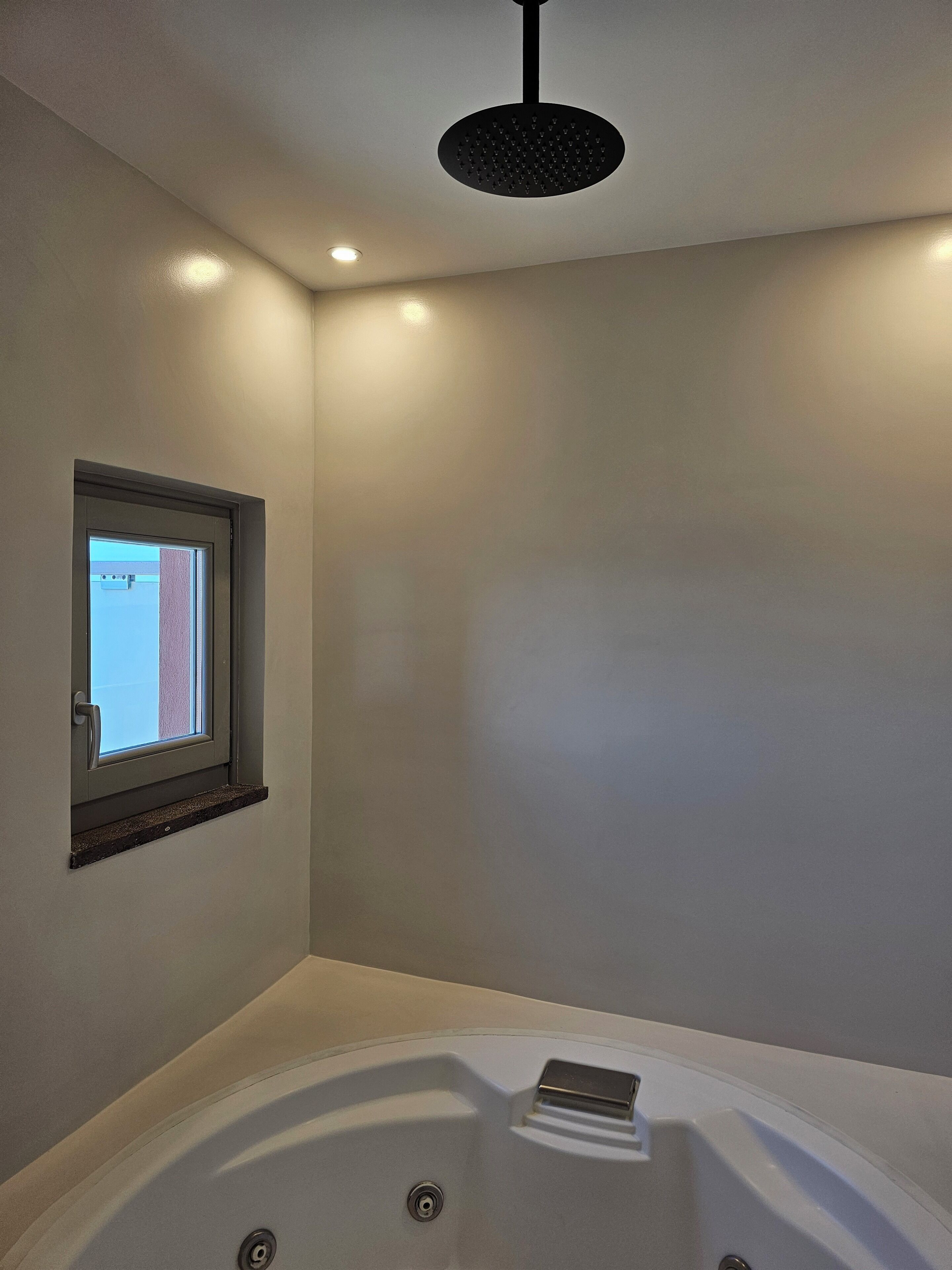 Une salle de bain avec une baignoire, une fenêtre et un luminaire au plafond.