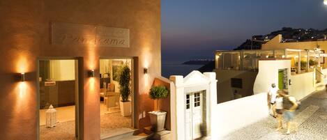 L’entrée d’un hôtel, avec une enseigne indiquant « Panorama Hotel », et une vue sur la mer en arrière-plan.