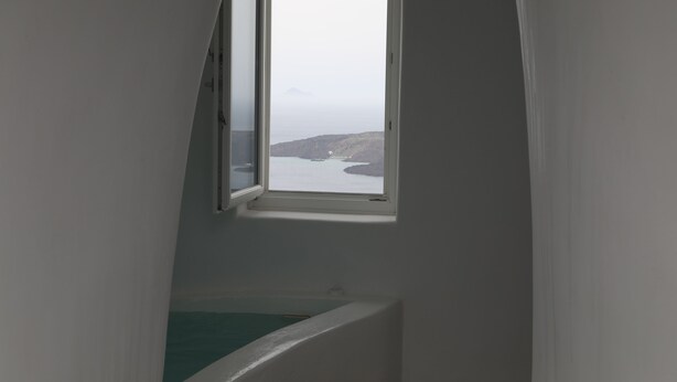 A narrow stairwell with a window overlooking a body of water and distant land.