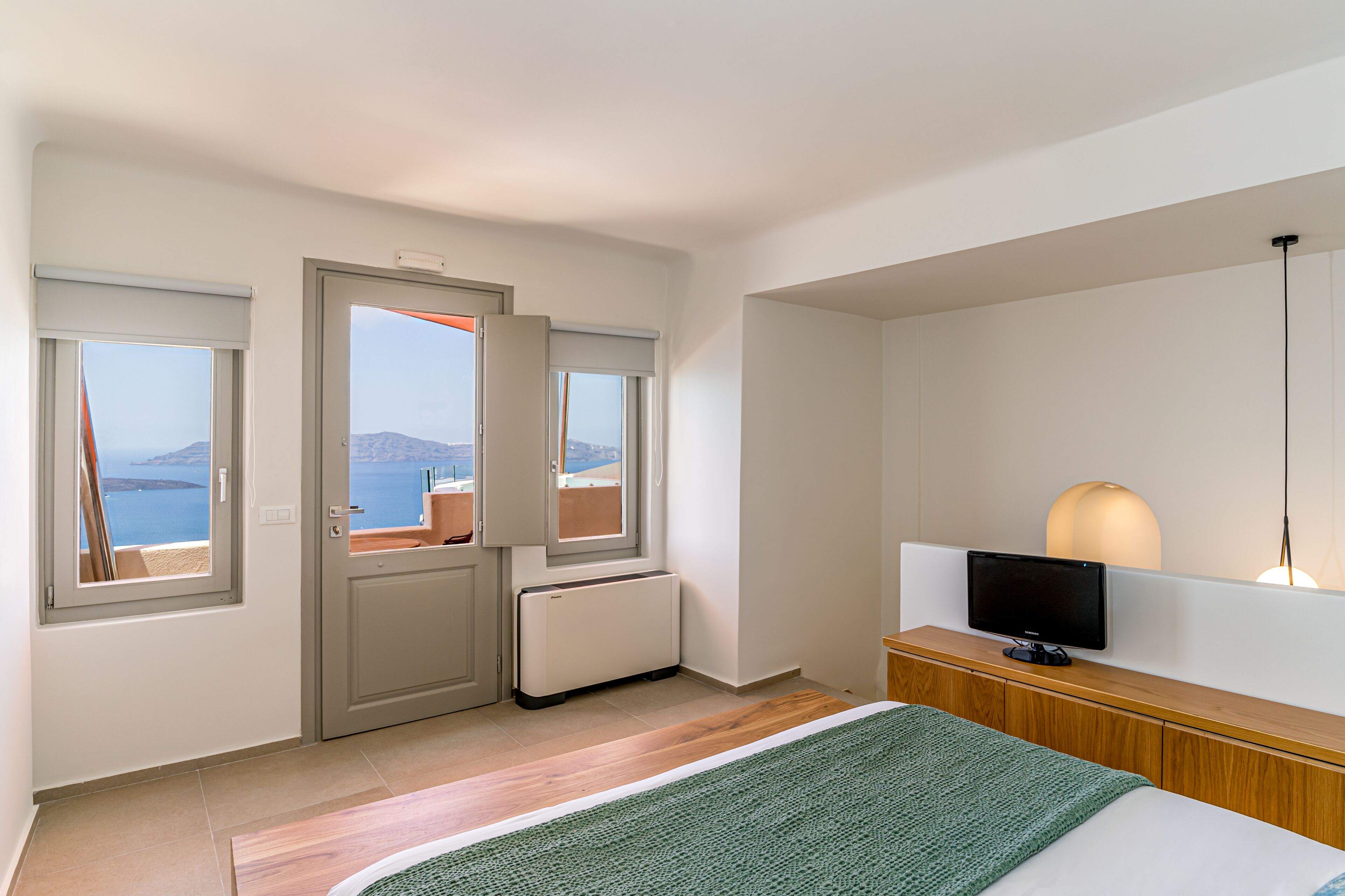 Une chambre d’hôtel avec un lit, une télévision, un radiateur et une fenêtre donnant sur la mer.