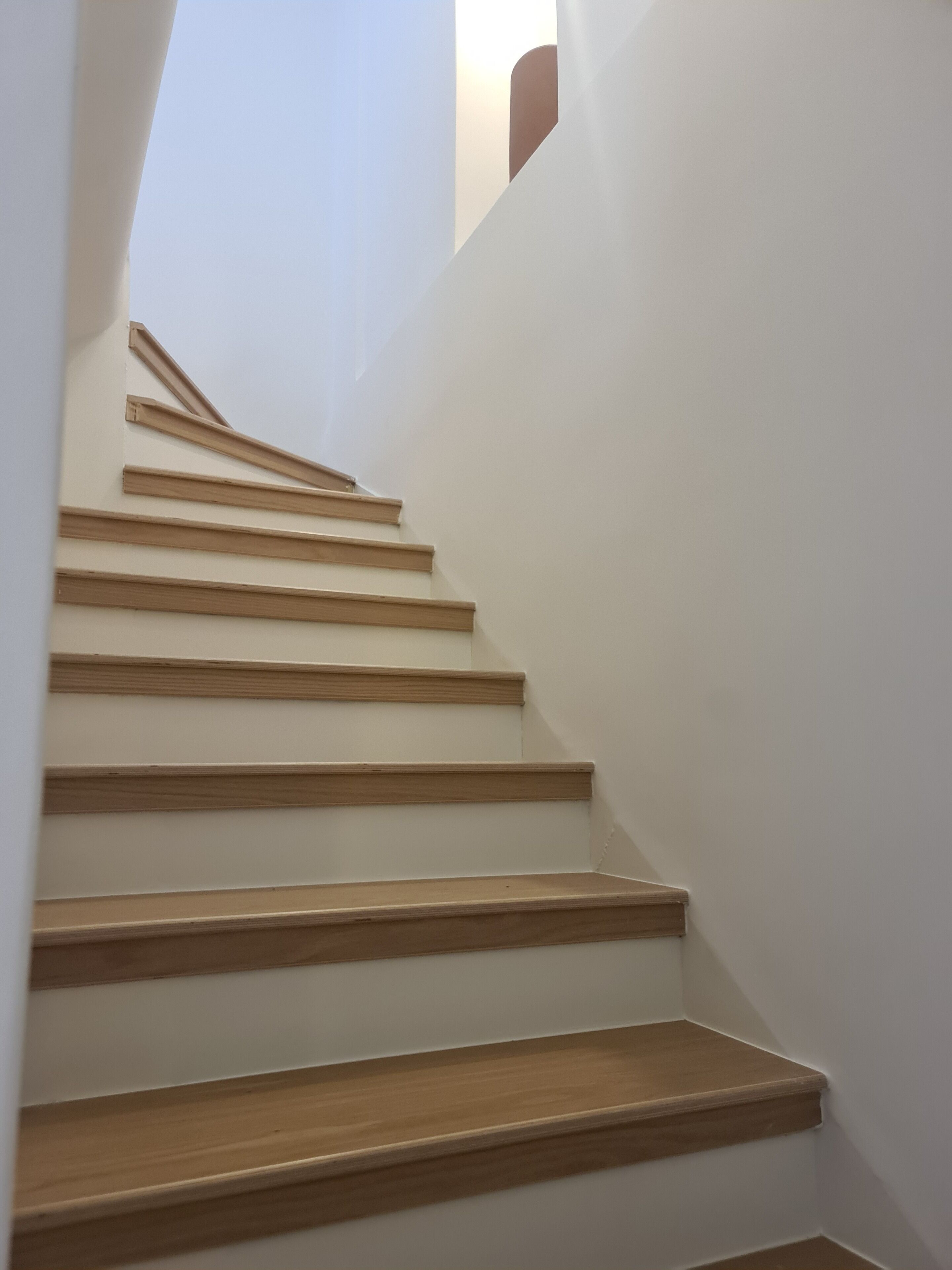 A staircase with wooden steps and white walls.