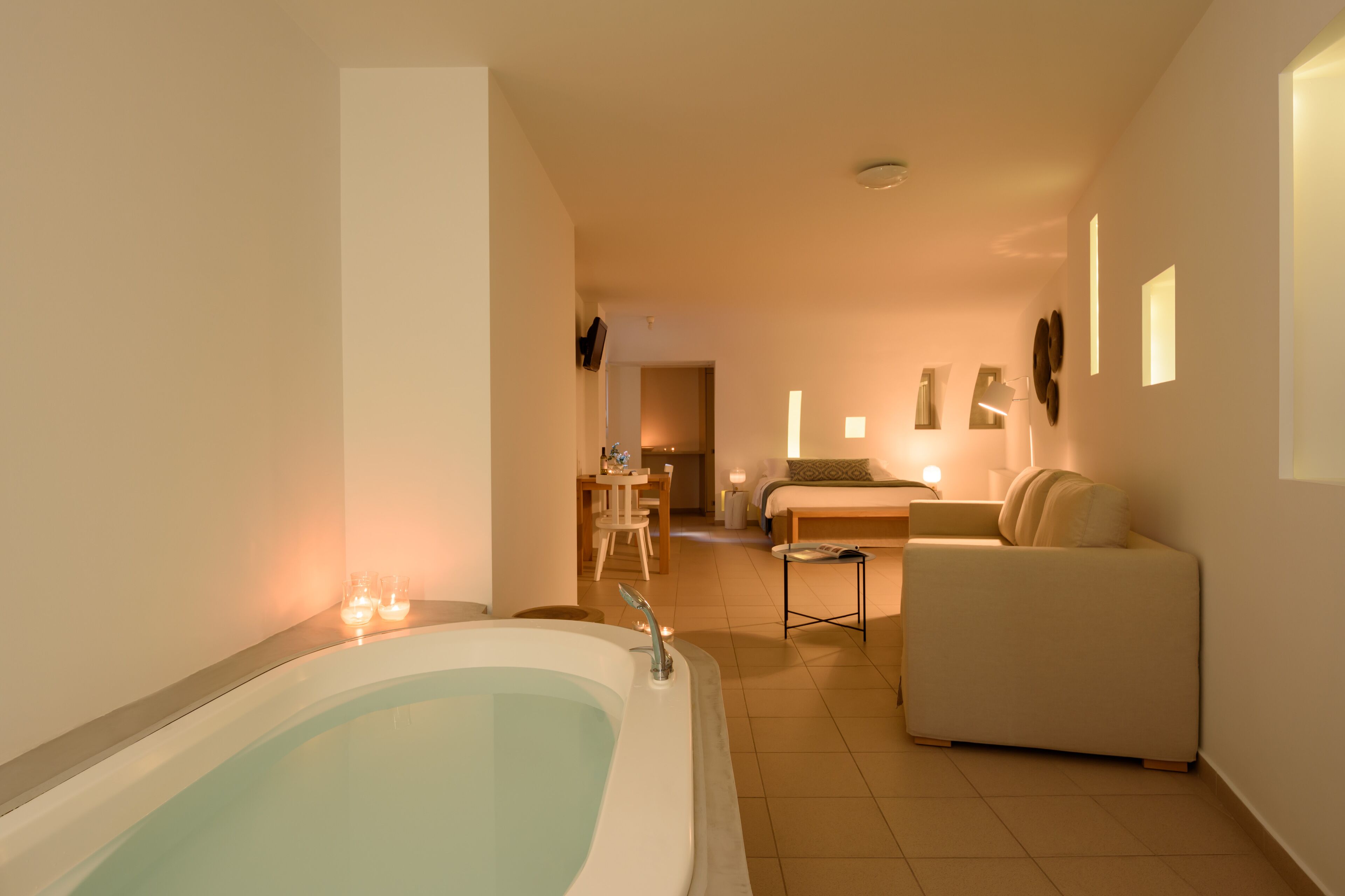 A modern bathroom with a large bathtub, a sofa, and a small table.