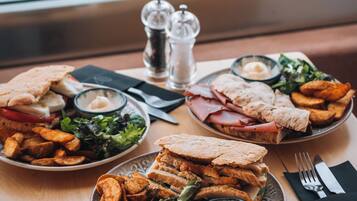 Une table où l’on voit un repas composé de sandwichs, de frites et d’une salade.