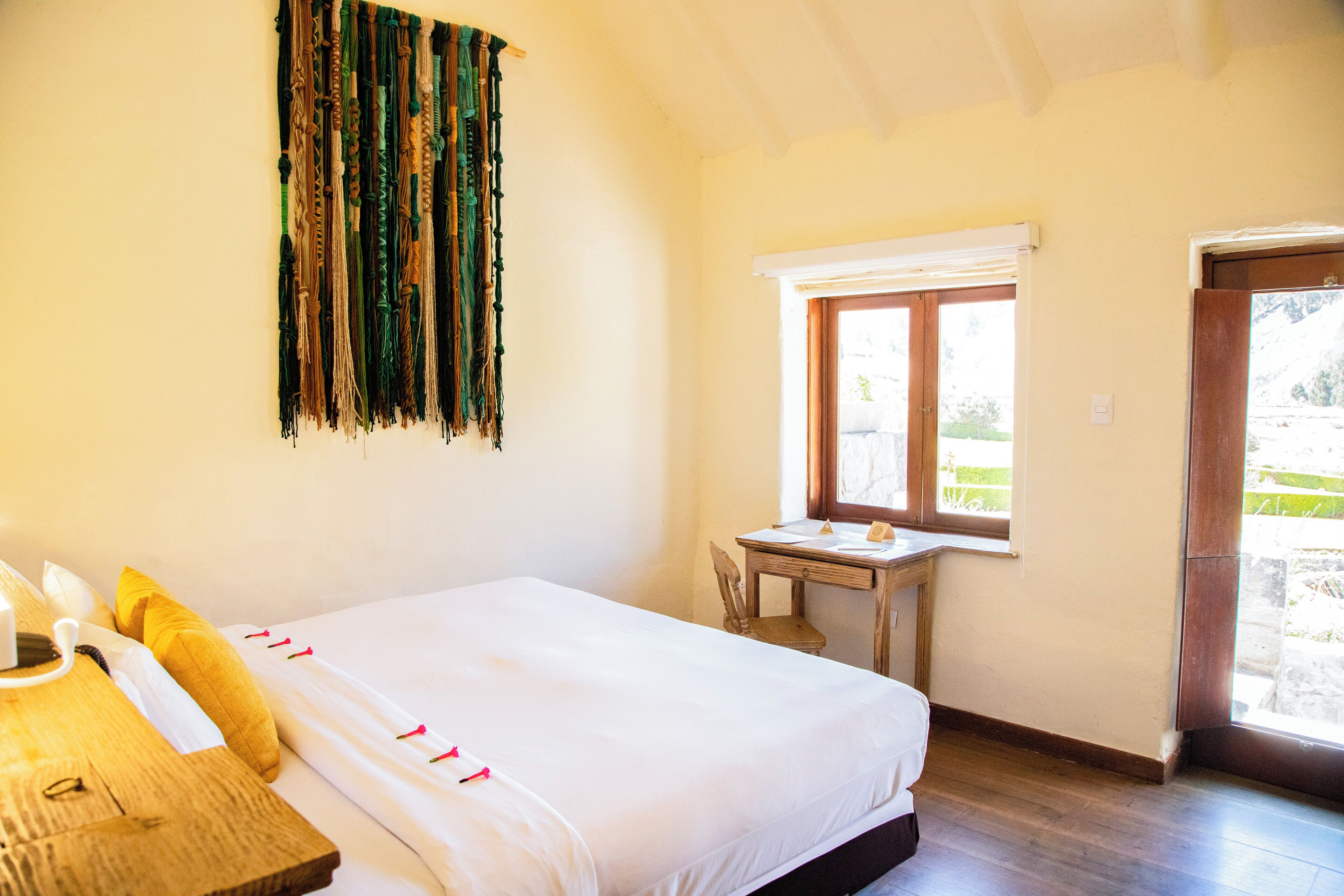 A bedroom with a bed, a wooden nightstand, a window, and a door.