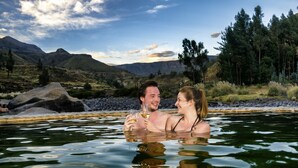 Una pareja en un manantial termal, con un paisaje montañoso de fondo.