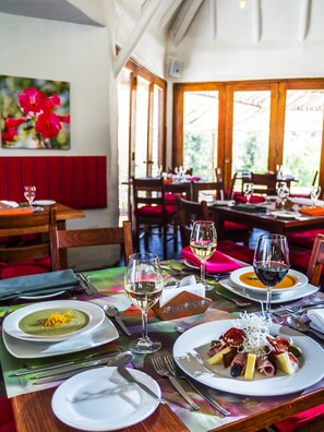 Een restaurantinterieur met gedekte tafels, diverse gerechten en wijnglazen.