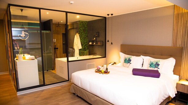 Une chambre d’hôtel moderne dotée d’un grand lit, d’une douche à parois de verre et d’une salle de bain ouverte.