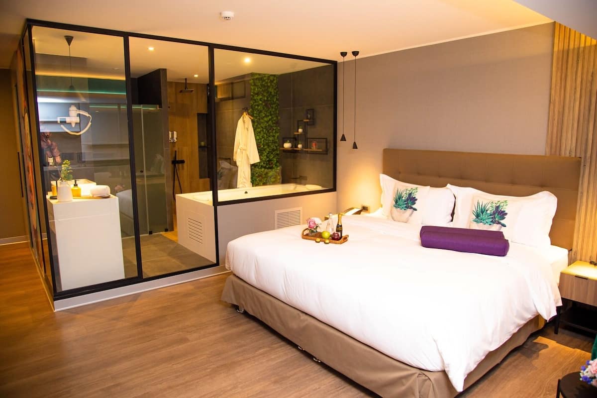 Une chambre d’hôtel moderne dotée d’un grand lit, d’une douche à parois de verre et d’une salle de bain ouverte.