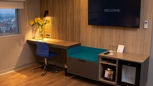 Un espace de bureau moderne comprenant un bureau, une chaise et un téléviseur affichant le mot « BIENVENUE ».