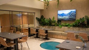 Un espace intérieur moderne doté d’une piscine, de coins salon et d’un téléviseur fixé au mur.