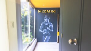 L’entrée d’une salle de sport, avec une affiche représentant une athlète, une porte et une fenêtre donnant sur un espace verdoyant.