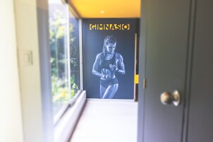 Entrada de uma academia, com um cartaz de uma atleta e uma janela que dá para o verde.