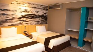 Una habitación de hotel con dos camas, un mural en la pared, un armario y una mesita de noche pequeña.