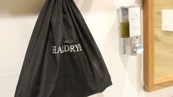 Un sac noir à cordon de serrage sur lequel est inscrit le mot « HAIDRYL », et qui est accroché à un mur.