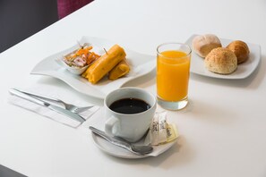 Een ontbijt met een kop koffie, een glas sinaasappelsap, een bord croissants en een kleine salade.