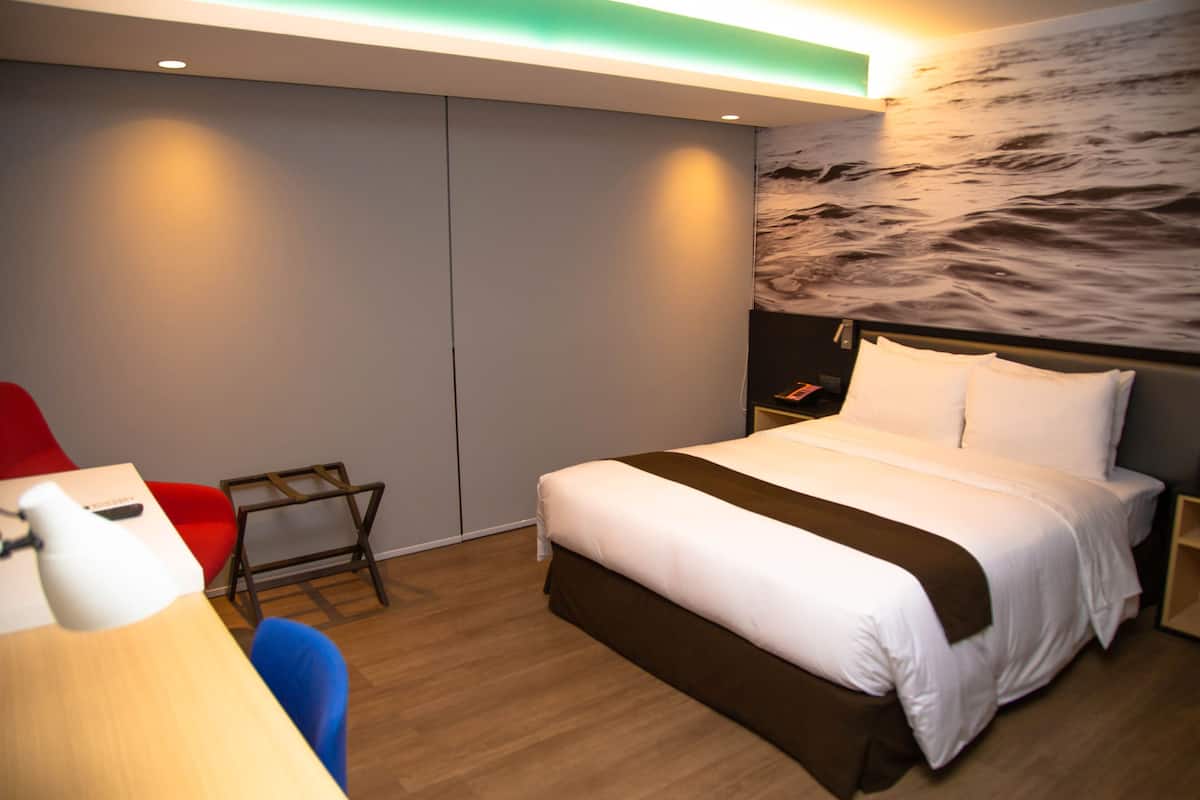 Une chambre d’hôtel moderne, dotée d’un grand lit, d’un bureau et d’une chaise.