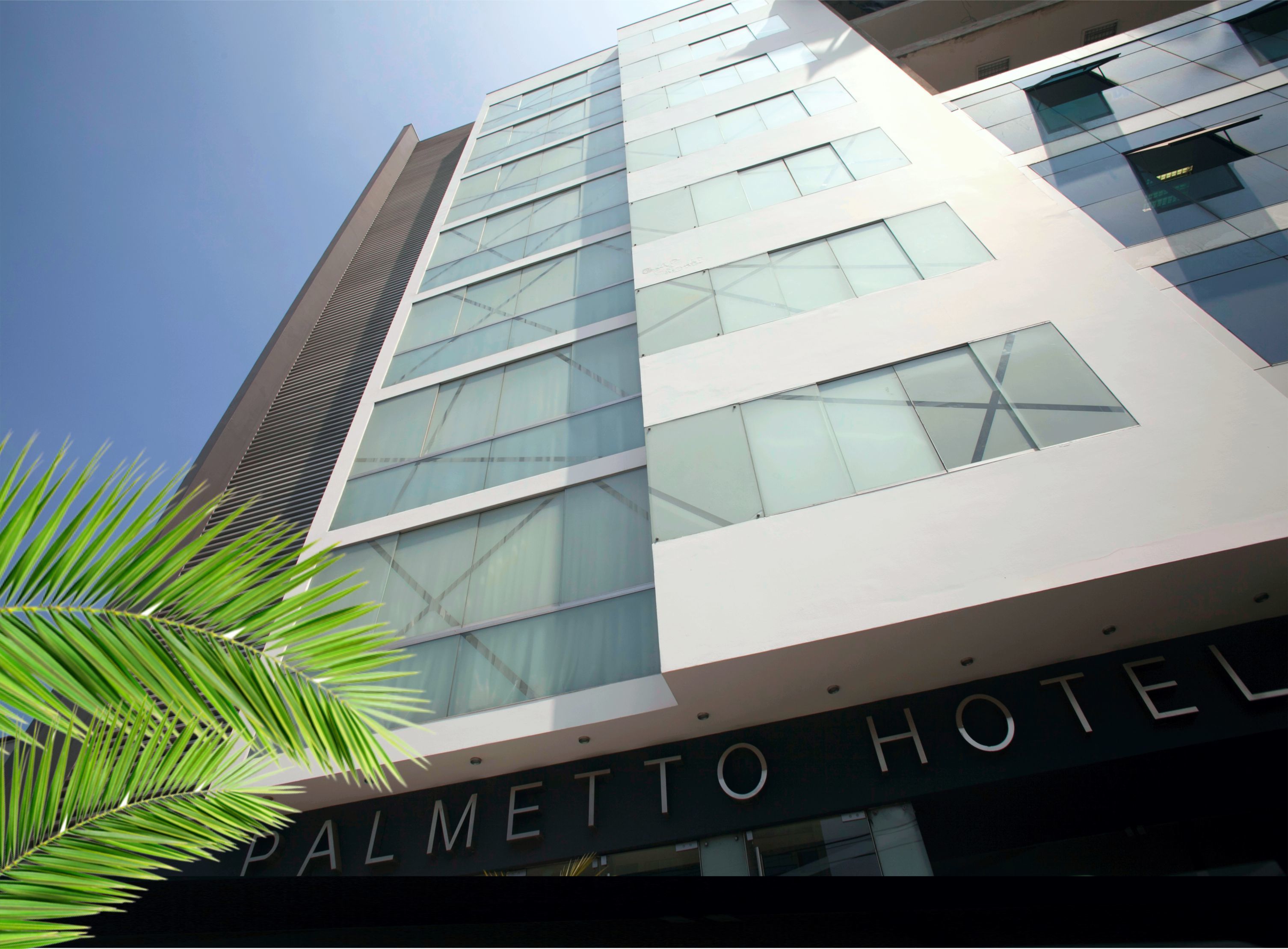 A modern hotel building with a prominent sign reading "PALMETTO HOTEL".