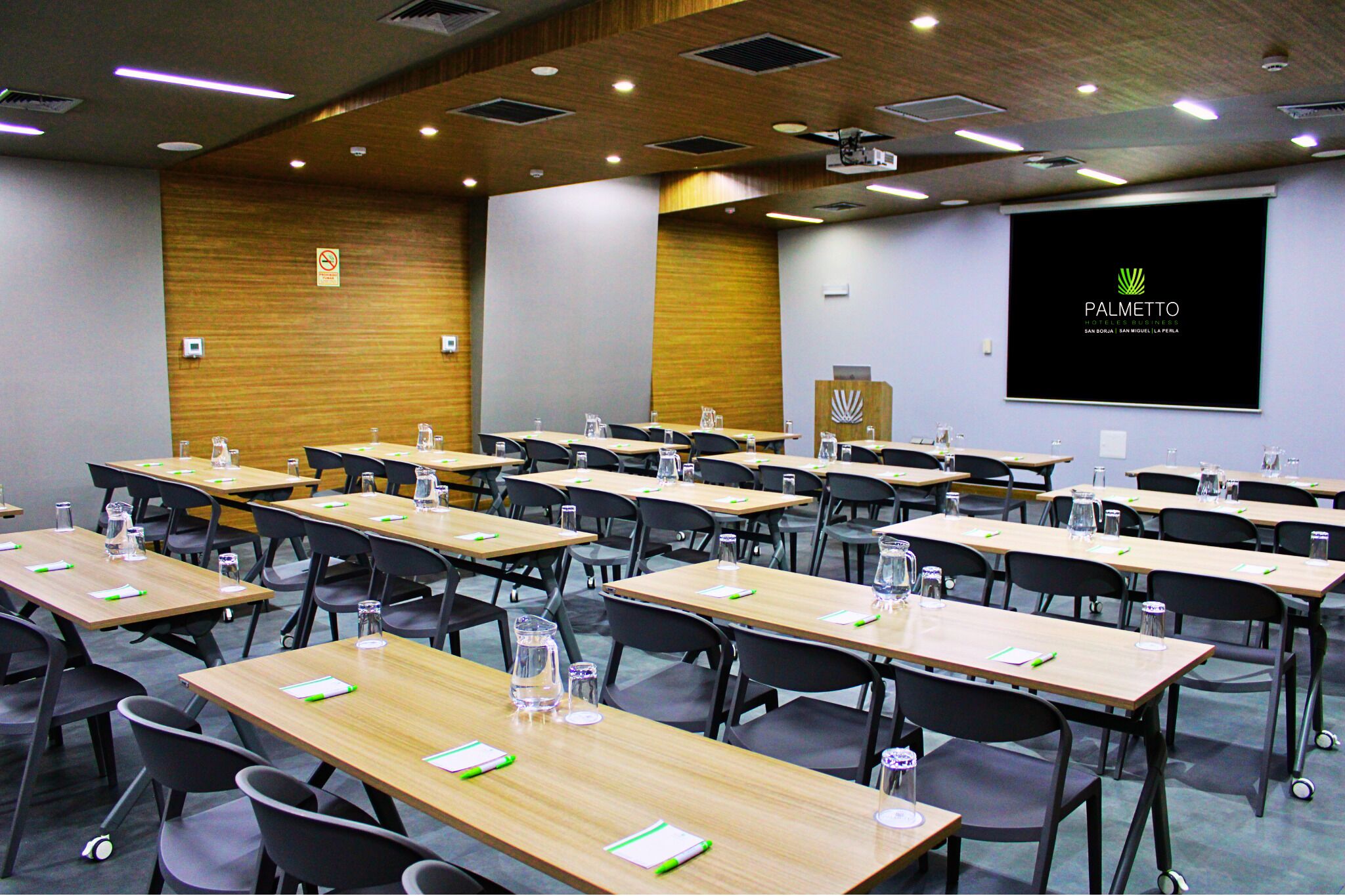 Une salle de conférence équipée de plusieurs tables, de chaises et d’un écran de projection affichant le mot « PALMETTO ».