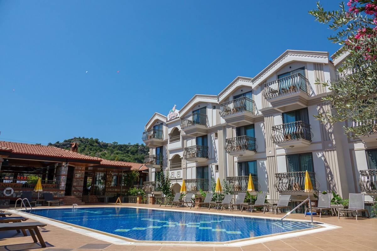 A hotel with a swimming pool, multiple balconies, and outdoor seating.