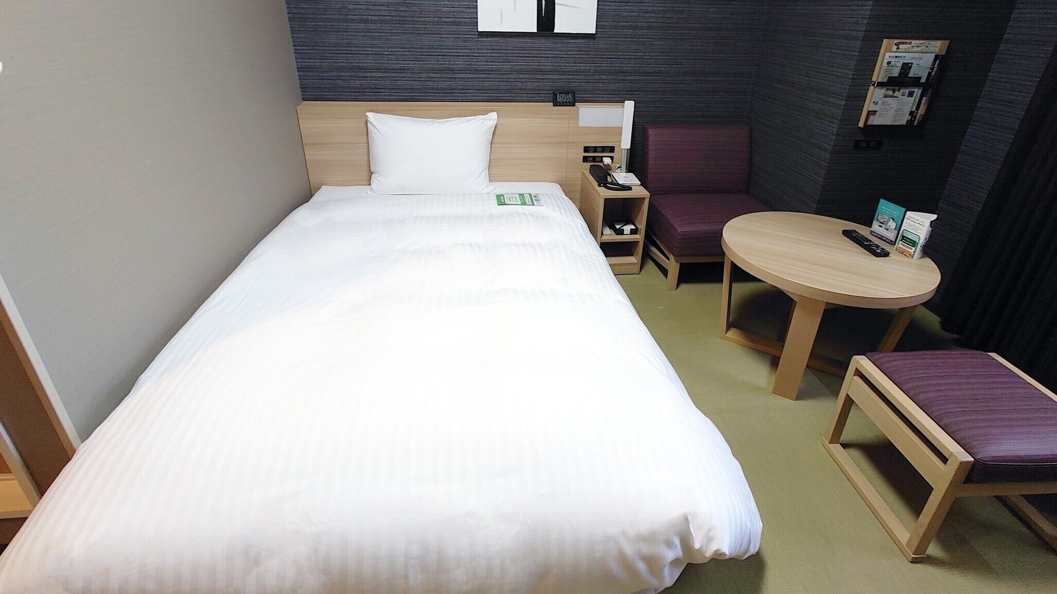 Een hotelkamer met een bed, een bureau, een stoel en een tafeltje.