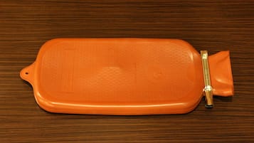 A rectangular orange object with a zipper on a wooden surface.