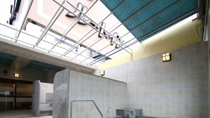 An indoor swimming pool with a tiled floor, a metal handrail, and a skylight above.
