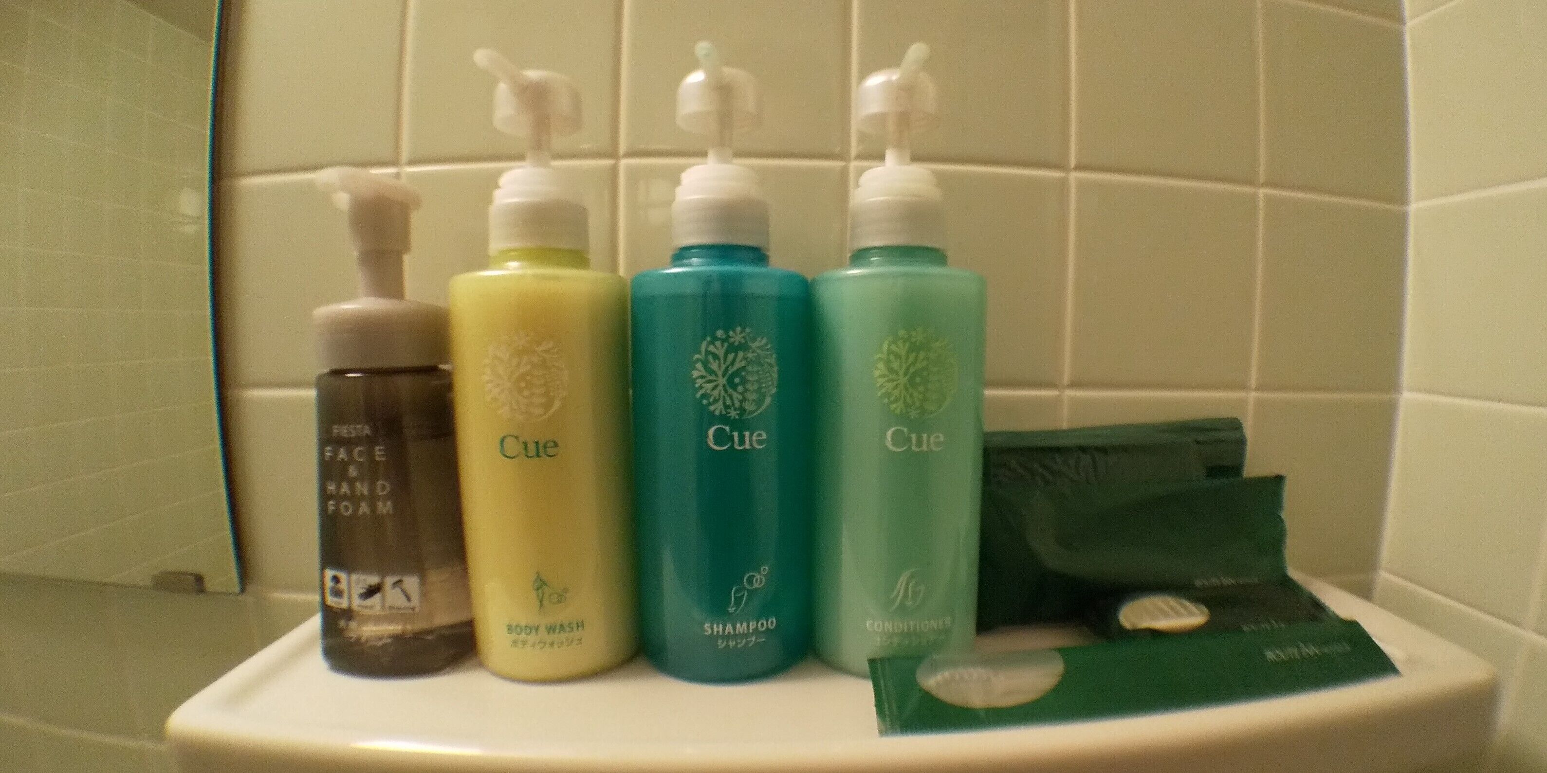 A bathroom shelf with various personal care products including body wash, shampoo, conditioner, and face foam.