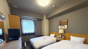A hotel room with two beds, a desk, a television, a window with curtains, a lamp, and a wall-mounted artwork.