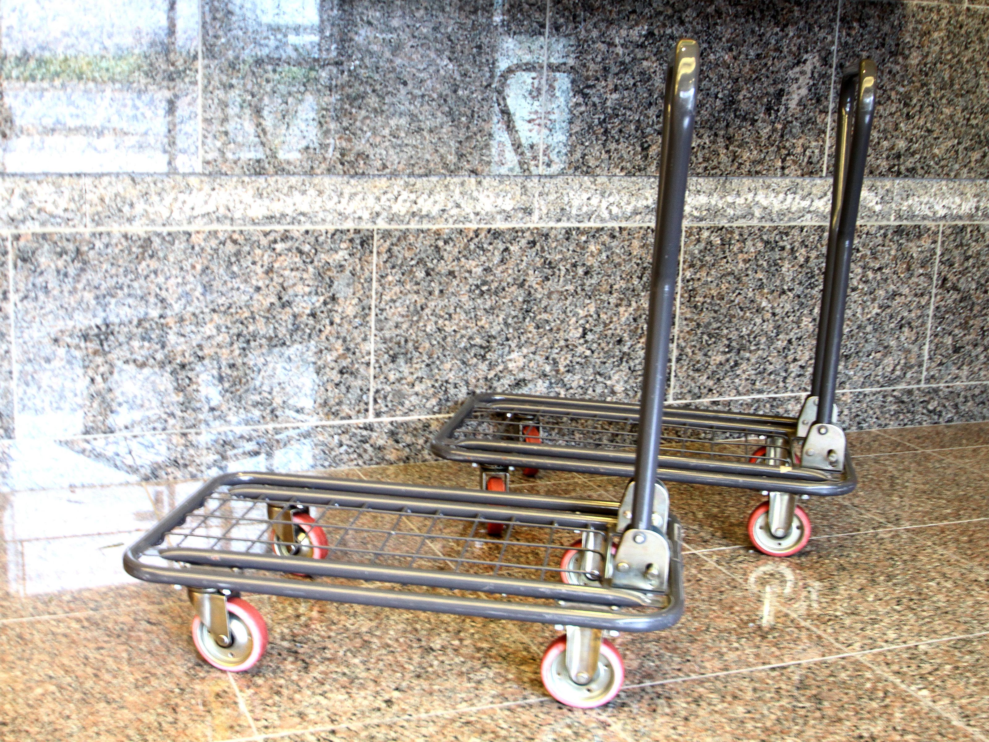 Two metal shopping carts with wheels on a granite floor.