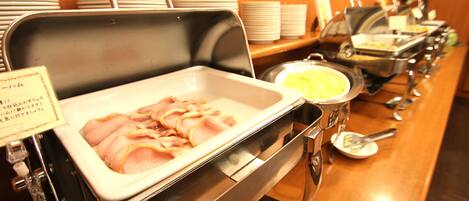 En buffet med forskellige retter, heriblandt skinke og en gryde suppe.