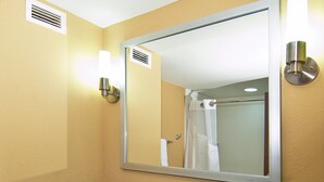 Un baño con lavamanos, espejo, toallero y artículos de aseo.