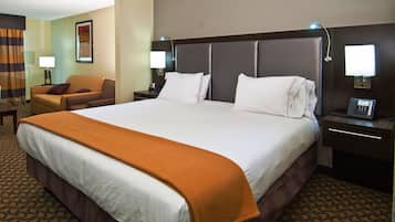 Une chambre d’hôtel avec un grand lit, deux tables de chevet avec des lampes, une chaise et un téléphone fixé au mur.
