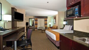 A hotel room with a desk, chair, bed, TV, microwave, and a bathroom. - Holiday Inn Express & Suites Jackson / Pearl Intl Airport by IHG (Pearl)