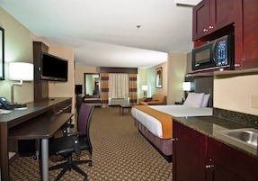 Una habitación de hotel con escritorio, silla, cama, televisor, microondas y baño.