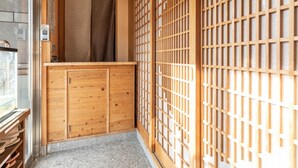 Una habitación tradicional japonesa con puertas correderas de madera, un pequeño mostrador de madera y un ventanal que da a un balcón.