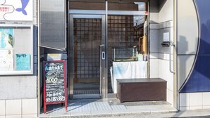 La entrada al Sparkling Dolphins Inn Kyoto, con un letrero de delfines, una puerta de cristal y un pequeño acuario en el exterior.