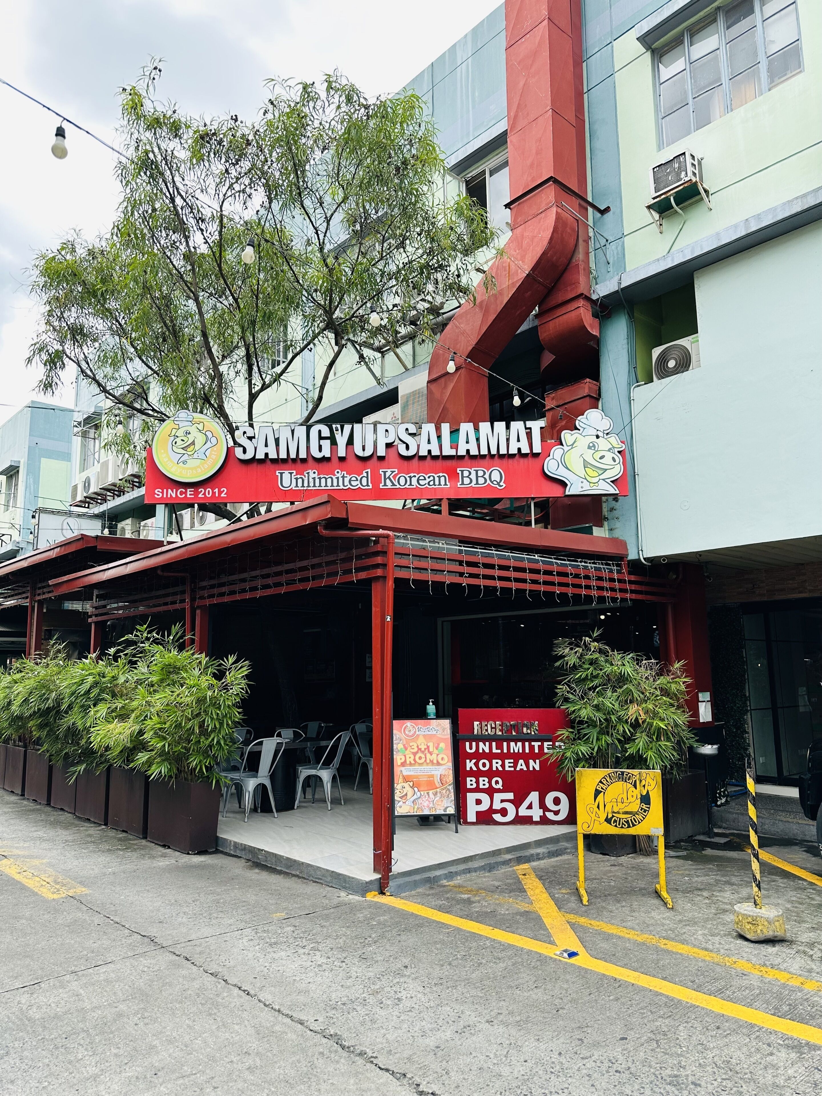 Un ristorante chiamato Samgyupsalamat con facciata rossa e insegna che pubblicizza barbecue coreano illimitato.