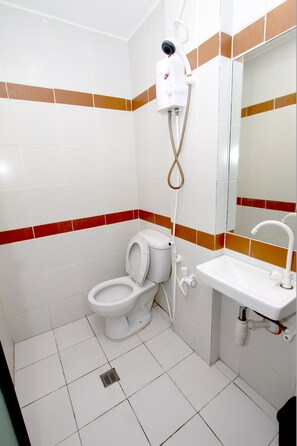 Un baño con inodoro, lavamanos y ducha de pared.