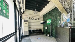 Un área de recepción con una pared verde, un reloj y un letrero DG.