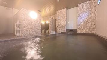 A large indoor swimming pool with tiled walls and a wooden ceiling.