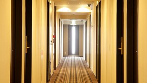 A hotel hallway with carpeted floors, doors on both sides, and overhead lighting. - Hotel Keihan Sapporo (Sapporo)