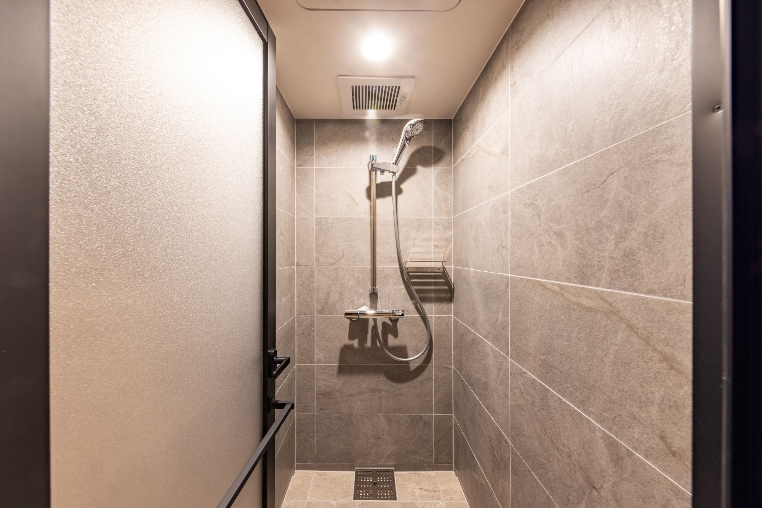 A small, enclosed shower area with a handheld showerhead and a wall-mounted faucet.