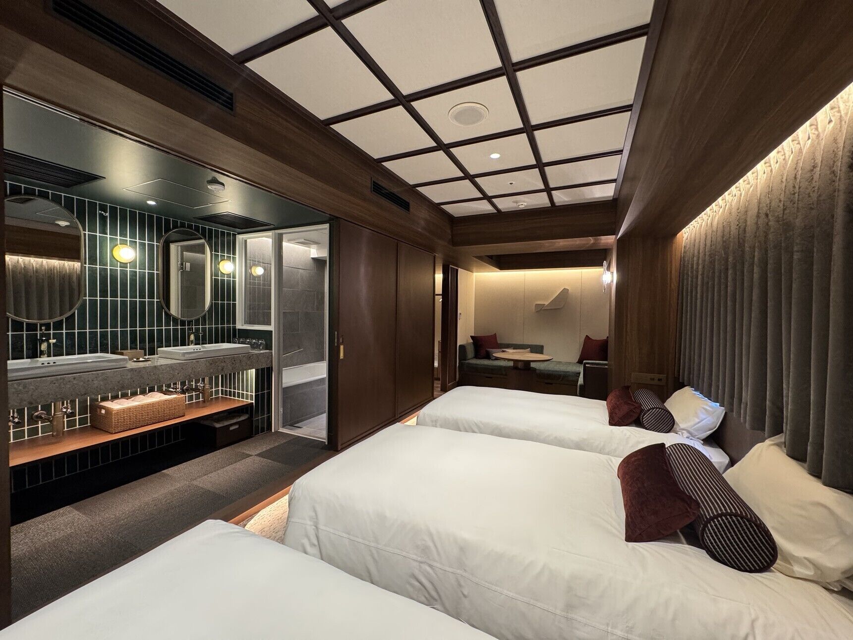 Habitación de hotel con una cama grande, baño independiente, zona de estar y techo con diseño de cuadrícula.