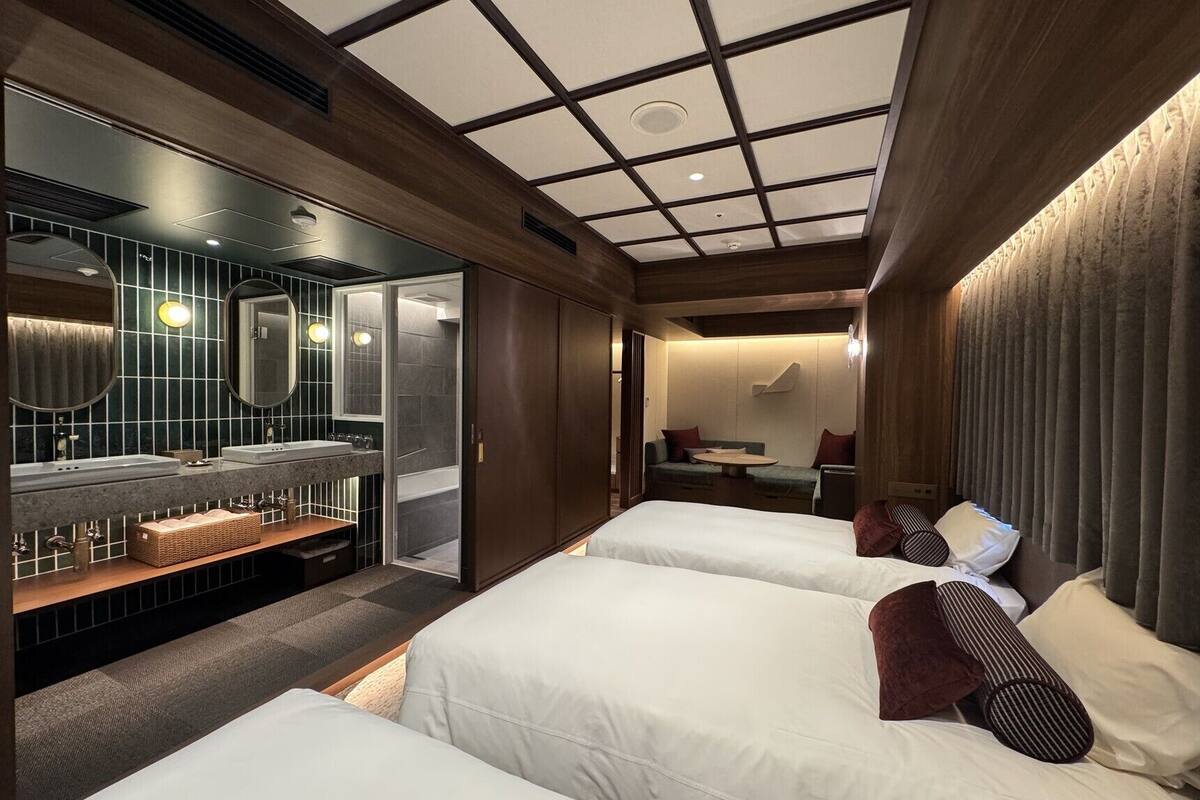 A hotel room with a large bed, a separate bathroom, a seating area, and a ceiling with a grid pattern.